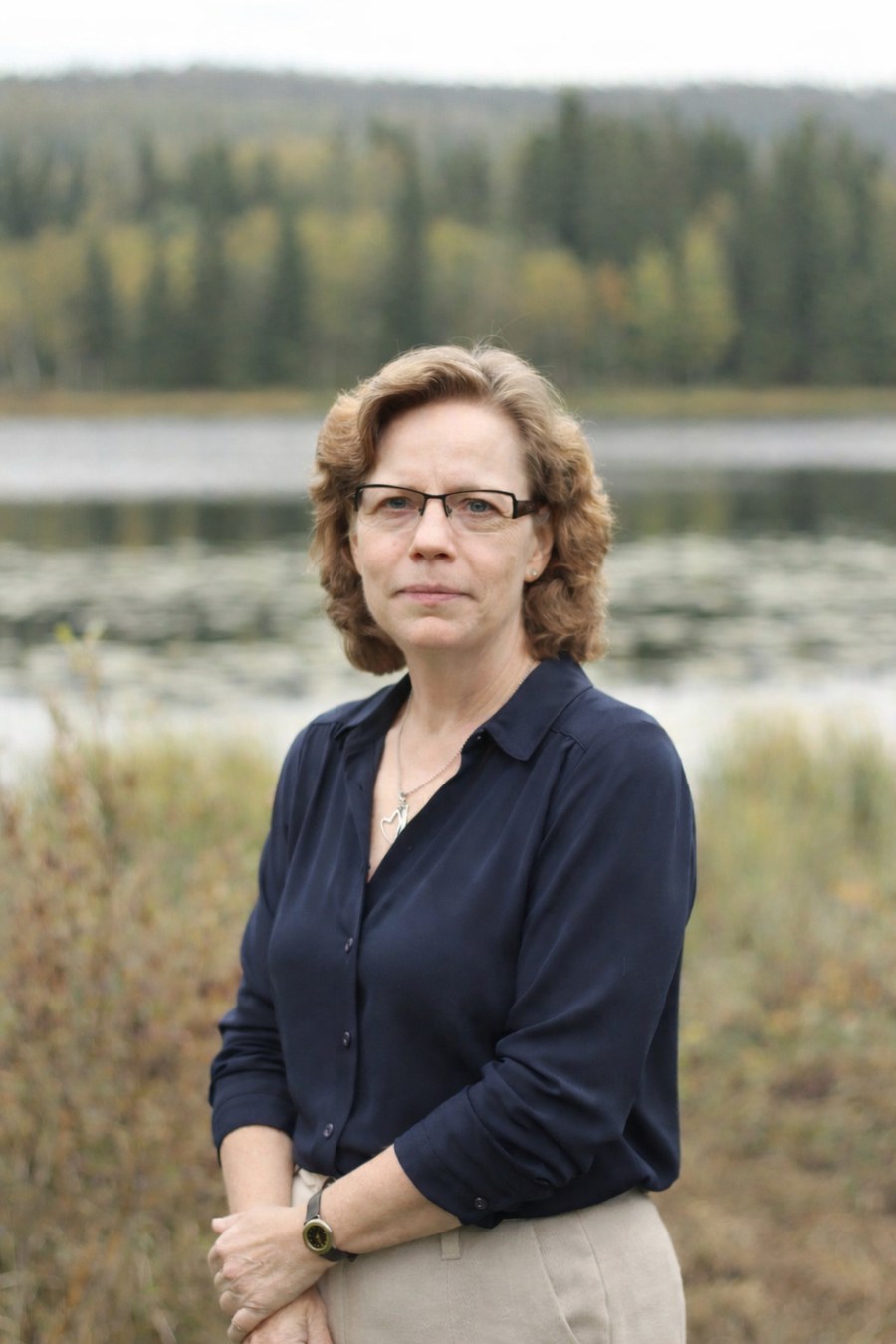Britt-Inger Jonsson, grundare av BitWeb24, står vid en sjökant med skog i bakgrunden.