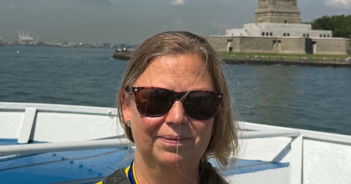 Susanne Petersson i solglasögon på en båt i New York, med Frihetsgudinnan i bakgrunden.